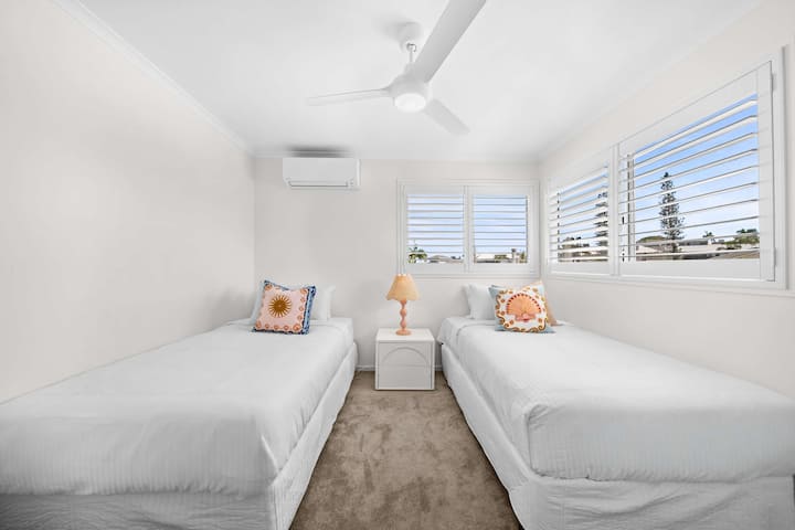 Une chambre côtière confortable idéale pour les enfants, avec deux lits simples King Size, la climatisation, une armoire et un ventilateur de plafond.