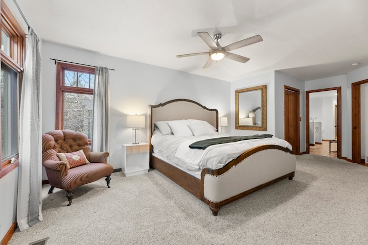 Priestranný apartmán plný slnečného svetla s mäkkým kobercom, útulným kreslom a stropným ventilátorom