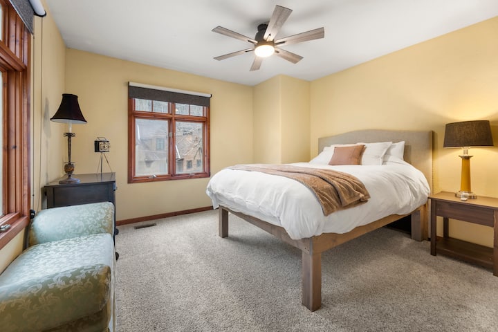 Slnečná, útulná spálňa s manželskou posteľou Queen, stropným ventilátorom a mäkkým kobercom.