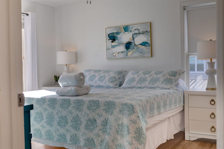 מבט נוסף על חדר השינה הראשי למעלה, מעוצב בקפידה ללילה של מנוחה לאחר יום על החוף