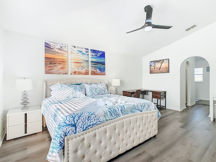 جناح أساسي أنيق مع سرير بحجم كوين وأعمال فنية ساحلية وشعور هادئ ومتجدد الهواء.