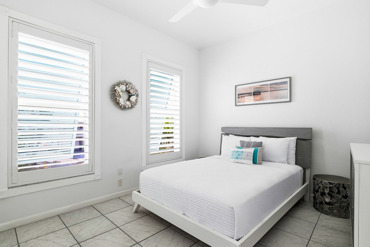 Pumzika katika chumba chako cha kulala chenye amani kilicho na kitanda kizuri cha malkia, mashuka meupe, na vizingiti vya mashamba vinavyokuwezesha kudhibiti mwanga wa asili kikamilifu.