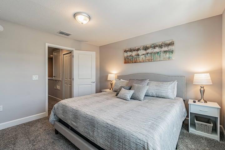 Disfruta de la tranquilidad en este espacioso dormitorio, donde los suaves tonos grises y la acogedora ropa de cama invitan a la relajación. La luz natural resalta la decoración, mientras que dos lámparas junto a la cama proporcionan un brillo cálido para relajarse después de un día de aventura.