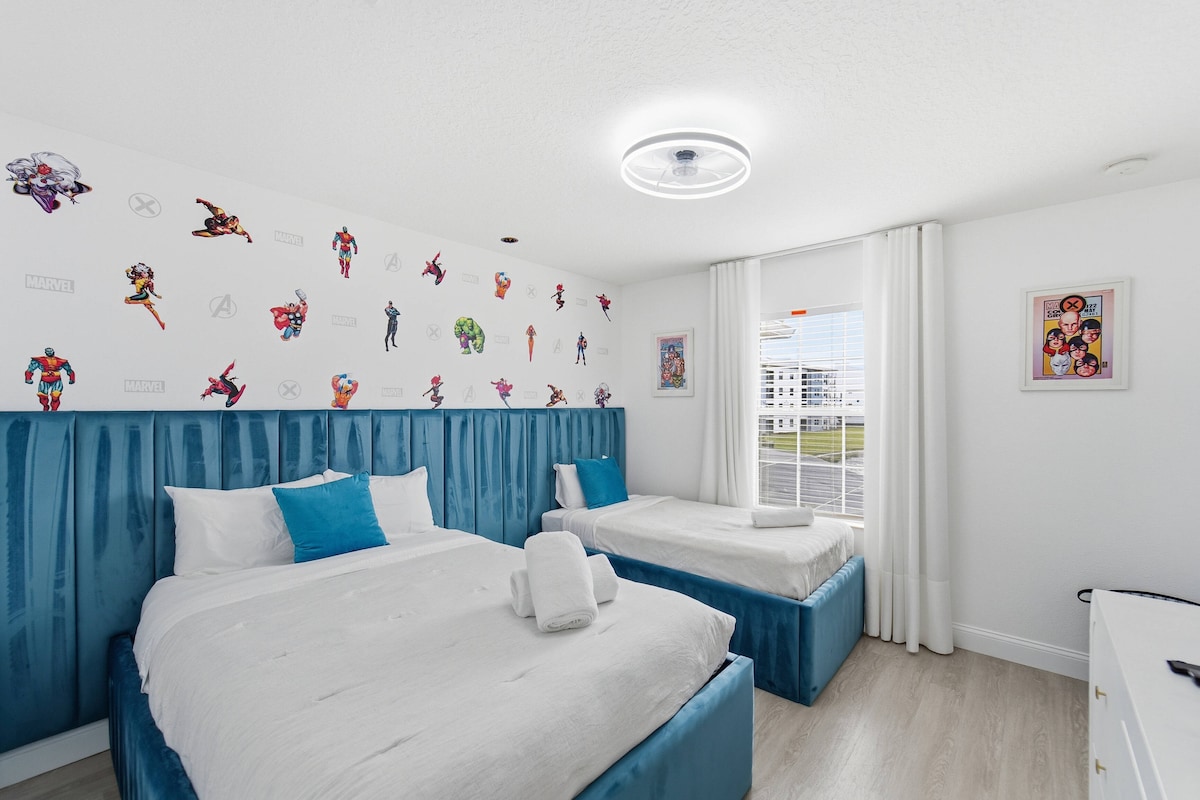 Este vibrante dormitorio cuenta con un divertido papel tapiz de superhéroes y acogedoras camas individuales con sábanas blancas y detalles en azul brillante. La luz del sol fluye a través de grandes ventanales, lo que lo convierte en un espacio alegre perfecto para aventuras memorables.