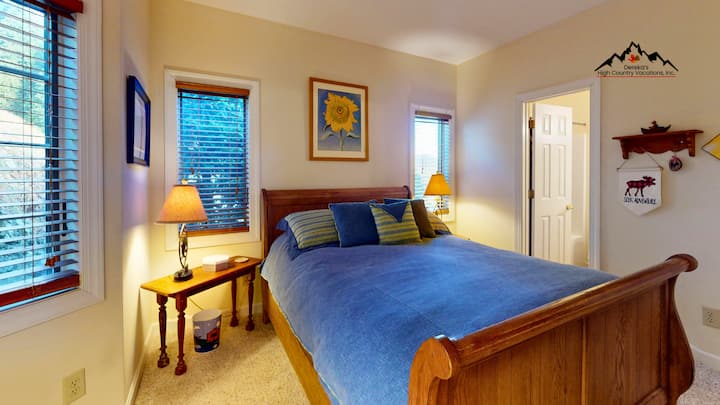 Отдайте се на сън в уютната си спалня с топли дървени мебели и успокояващи сини чаршафи, докато естествената светлина прониква през жалузите.