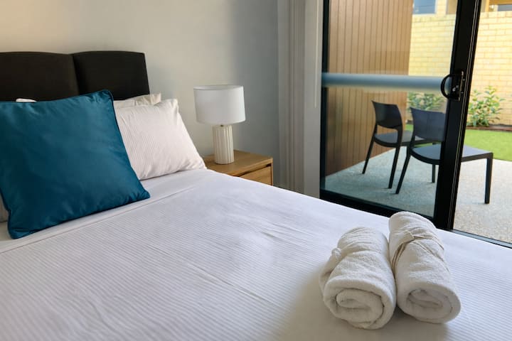 ห้องนอนที่สว่าง มีทางเข้าลานบ้านส่วนตัว ผ้าปูที่นอนสะอาด และผ้าเช็ดตัว