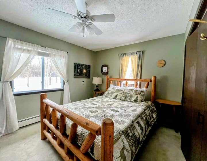 Chumba cha kulala cha kando ya ziwa chenye kitanda cha mbao na mandhari ya amani ya msitu