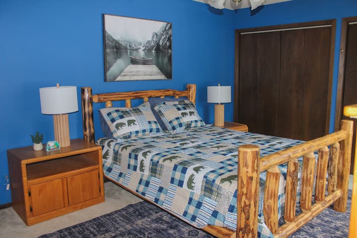 Chumba cha kulala chenye mwanga na kinachovutia chenye kitanda cha mbao na ukuta wa bluu—kinafaa kwa mapumziko ya usiku