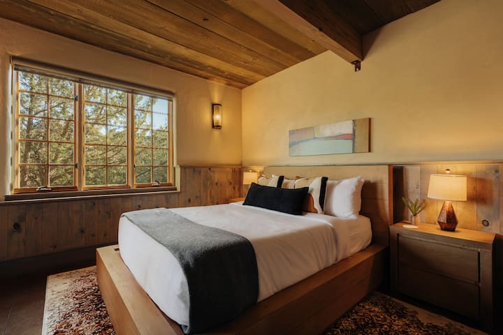 Sink into crisp linens beneath rustic wooden beams while forest views create your peaceful sanctuary.