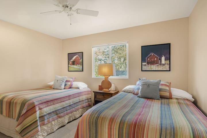 Спална соба со два кревета и рустикални уметнички дела.