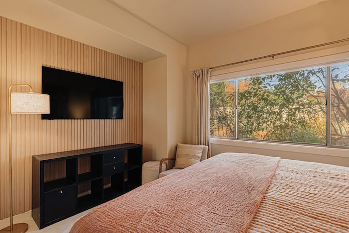 Utonite u san u toploj, modernoj spavaćoj sobi u kojoj se meke teksture stapaju s prirodnim drvom, a kroz prozore se pruža pogled na miran vrt.