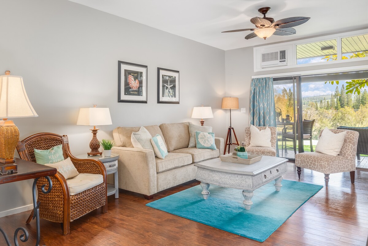 Ontspan in een lichte woonkamer met een gezellige bank, rotan fauteuils en glazen schuifdeuren die naar buiten openen.