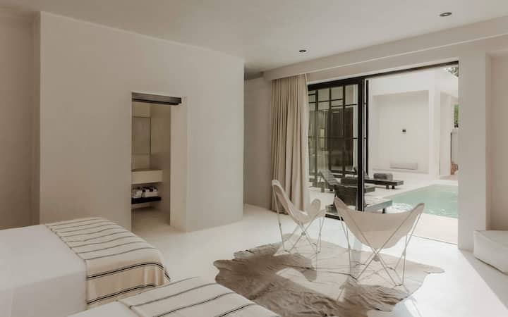 Spálňa s manželskými posteľami, posuvnými sklenenými dverami a mäkkými neutrálnymi farbami.