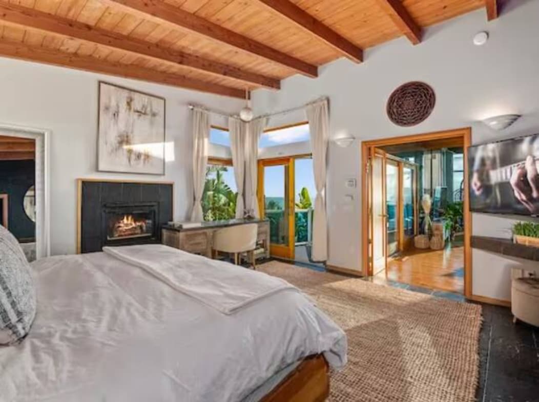 Мирно одморалиште каде што удобноста се среќава со елеганцијата - креветот ве поканува да се опуштите додека гледате во бескрајниот океан низ големи стаклени врати. Модерен камин и дрвен таван внесуваат топлина и карактер во оваа светла, пространа соба.