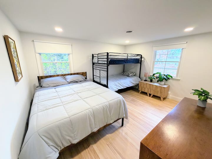 Sunny family bedroom with queen + bunks, wood floors, and storage.
