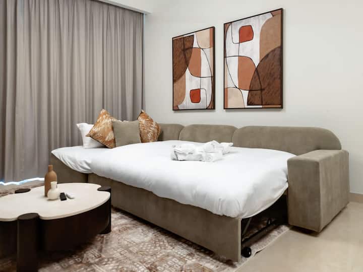 Relájate en la sala de estar con un gran sofá, que se puede usar como sofá cama, y amplias ventanas con vistas al horizonte durante tu estancia en Dubái. El diseño abierto y la luz natural crean un entorno fácil para descansar, leer o disfrutar de un espectáculo.