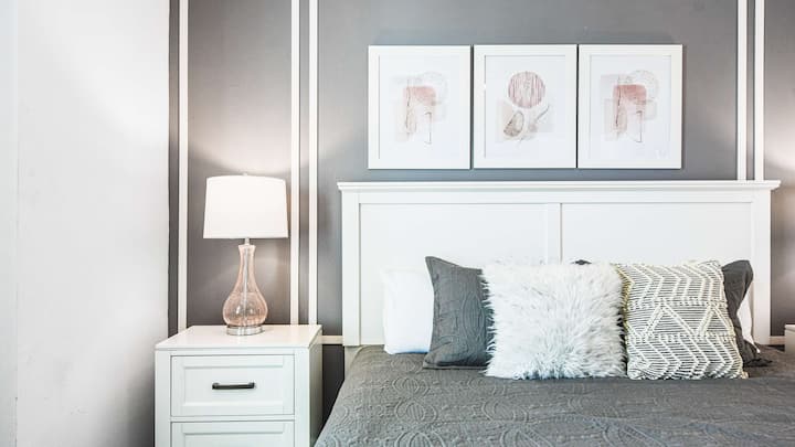 ห้องนอนมุมที่หรูหรา พร้อมเตียงคิงไซส์ที่อบอุ่น โต๊ะข้างเตียงที่ทันสมัย แสงไฟที่นุ่มนวล และของตกแต่ง
