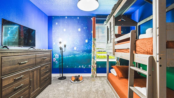 ห้องเด็กสองชั้นแปลกตา พร้อมภาพวาดดาว บ้านต้นไม้ เตียง แกะสลักไม้ และทีวี
