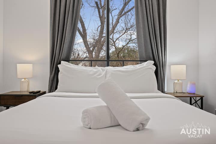 Opgerolde handdoeken begroeten je - fris beddengoed en uitzicht op de boomtoppen maken het af