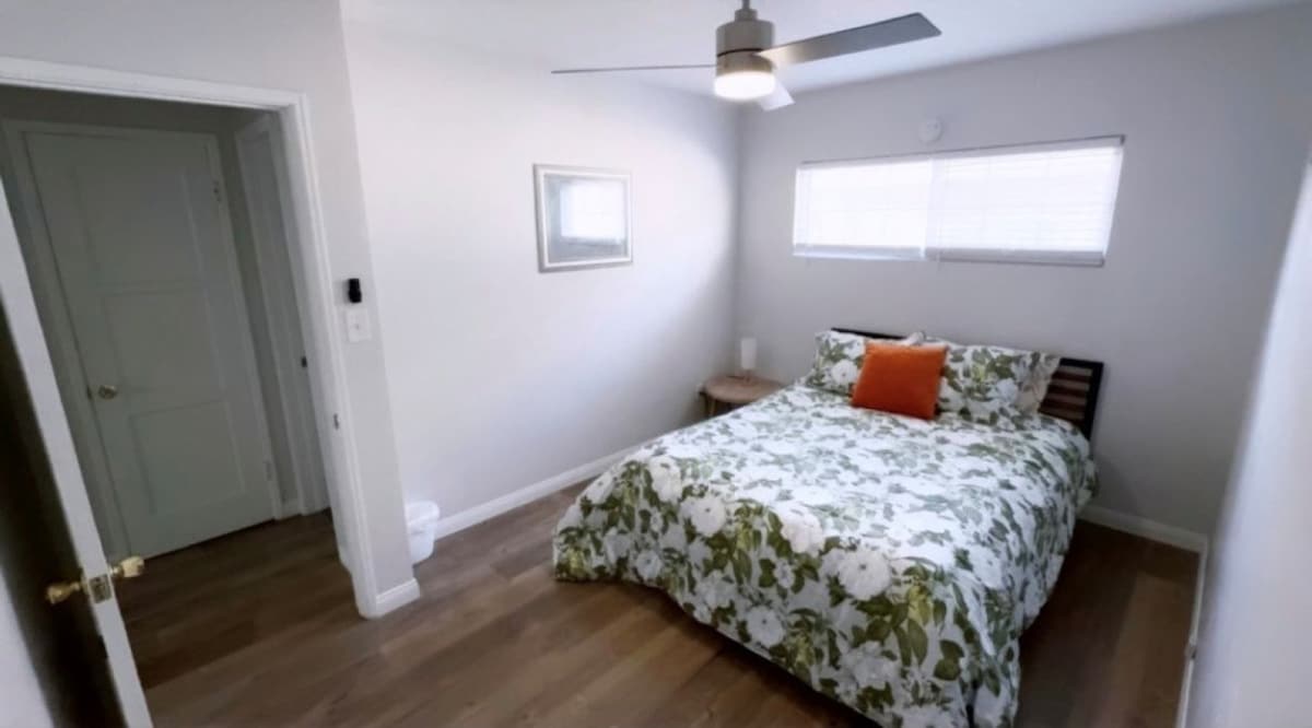 Svijetla, udobna spavaća soba s udobnim krevetom, modernim stropnim ventilatorom i prirodnim svjetlom osmišljenim za mirne noći nakon dana provedenog u istraživanju.