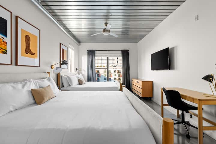 Relájate en tu elegante habitación con dos cómodas camas, un moderno espacio de trabajo y vistas a la ciudad desde la ventana.