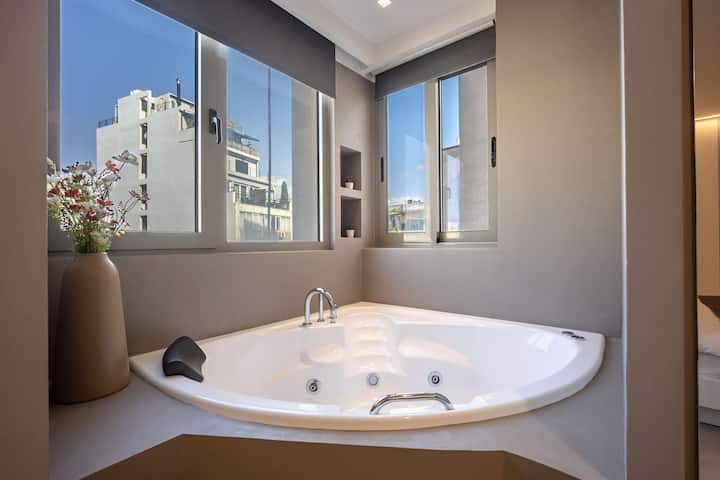 Джакузи в ъгъла с изглед към града, осигуряващо удоволствие от релаксация и незабравими моменти за пътуващите.