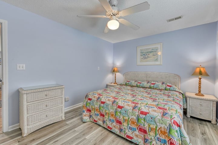 Dormitorio con ropa de cama de colores y televisor de pared