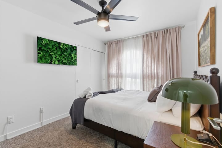 غرفة نوم ثالثة بها سرير بحجم كوين وتلفزيون ذكي وأثاث مريح وخزانة ملابس.