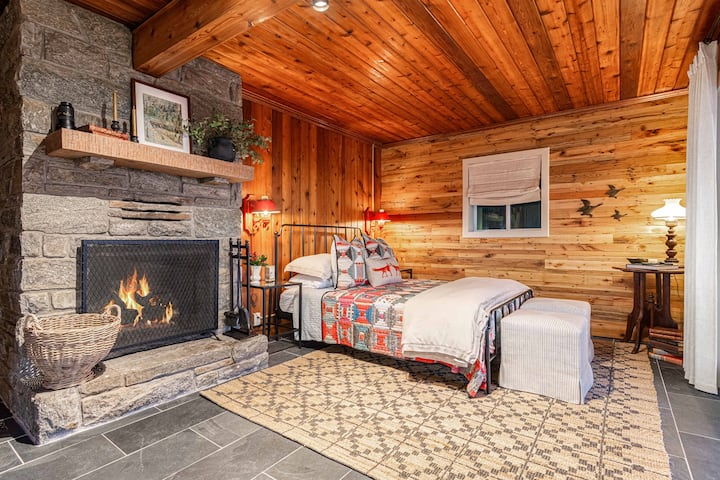 Útulná hlavná spálňa, kde sa rustikálne čaro stretáva s pohodlím, s kamenným kozubom, teplými drevenými stenami a mäkkou posteľou navrhnutou pre pokojné horské noci.