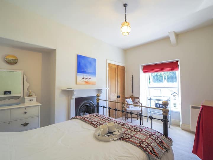 Dormitorio doble, cama plegable, tocador, silla y ventana.
