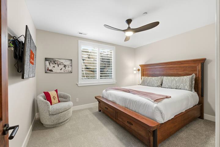 Dormitor pentru oaspeți cu cadru de pat din lemn și design confortabil:
Apartament cald cu mobilier rustic din lemn, ventilator de tavan și iluminat moale pentru un refugiu montan odihnitor.