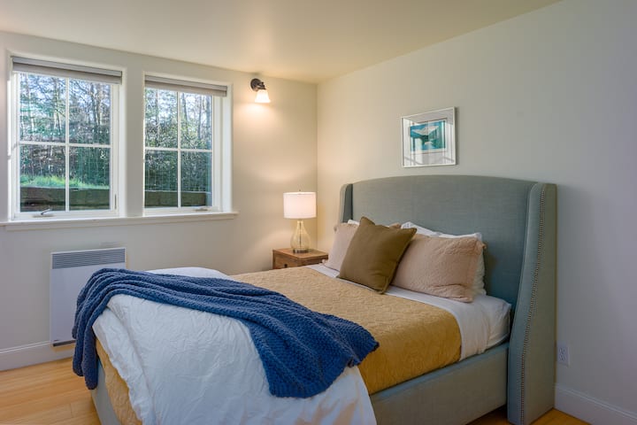 חדר שינה שלישי עם מיטת קווין סייז רכה, תאורה רכה ונופים שלוים של גינה לשינה שלווה.