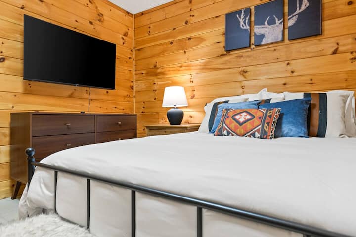 A quiet and cozy bedroom featuring a comfortable queen bed, warm wood walls, and soft lighting—perfect for a restful night’s sleep. This peaceful retreat offers a calm, private space to unwind after a day of exploring.