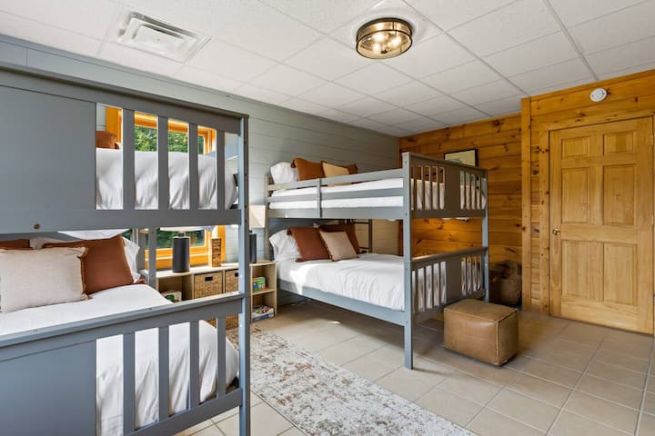 Perfect for kids or groups, this fun bunk room features four full-size beds, cozy reading spots, and a selection of games. A bright window adds natural light, creating a comfortable hangout space for relaxing, playing, or movie nights.