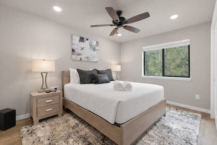 รายละเอียดที่ใส่ใจ เช่น พรมตกแต่ง โคมไฟข้างเตียง และการออกแบบที่สะอาด ทำให้ห้องนอนนี้เป็นสถานที่พักผ่อนที่อบอุ่น