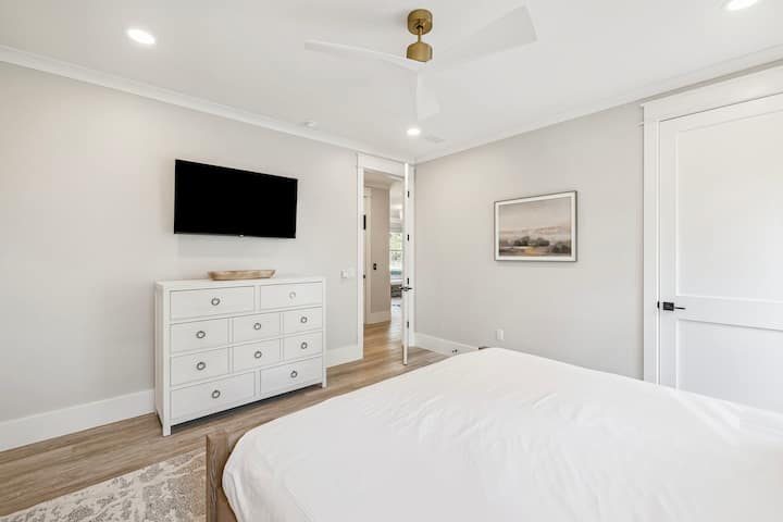 Te encantará despertarte en este dormitorio tranquilo con sábanas blancas y frescas, un televisor moderno y muebles elegantes que crean tu refugio perfecto.