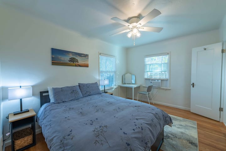 Descanse plácidamente en su dormitorio luminoso y espacioso, con ropa de cama cómoda, un ventilador de techo silencioso y un espacio de trabajo con luz natural.