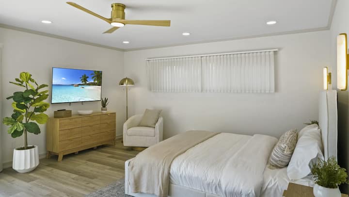 Chumba cha kulala cha msingi chenye kitanda aina ya king, kabati la kuingia, televisheni ya OLED ya 55" 4k, bafu la ndani na mandhari ya ufukweni.