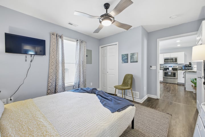 Udobna spavaća soba s TV-om, stropnim ventilatorom i izravnim pristupom modernoj kuhinji E