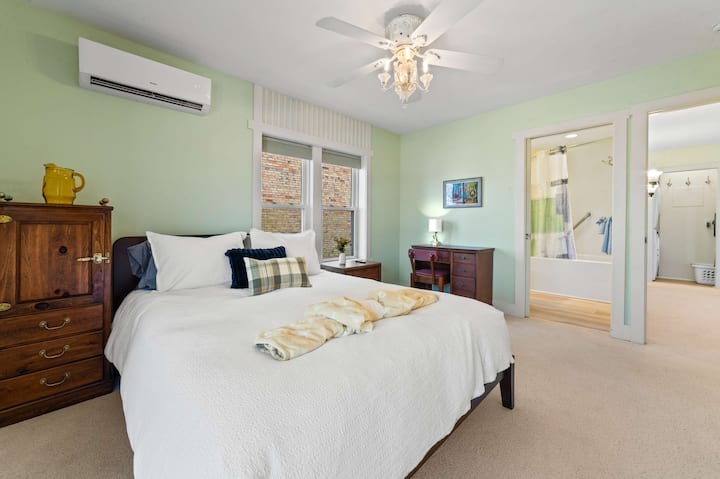 חדר שינה ראשי עם מיטת קווין סייז ואמבטיה מלאה.