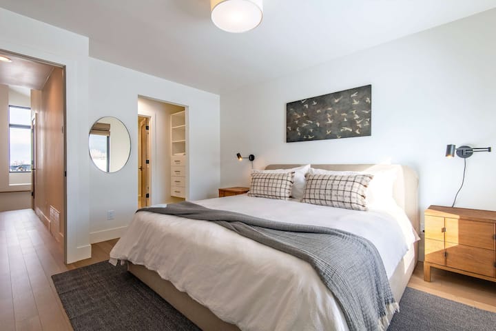 Cozy bedroom with dark headboard, warm reading lamp, and neutral tones — a quiet, restful retreat after a full day of Idaho adventure.