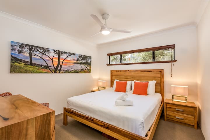 ห้องนอนที่สองที่ตกแต่งอย่างอบอุ่นและสวยงามพร้อมเตียงขนาดคิงไซส์โทนสีไม้ที่อบอุ่นและแสงที่นุ่มนวล