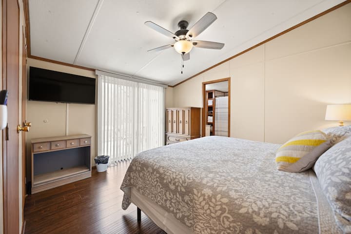 Dormitorio luminoso con TV, ventilador de techo, acceso al patio y pisos de madera noble