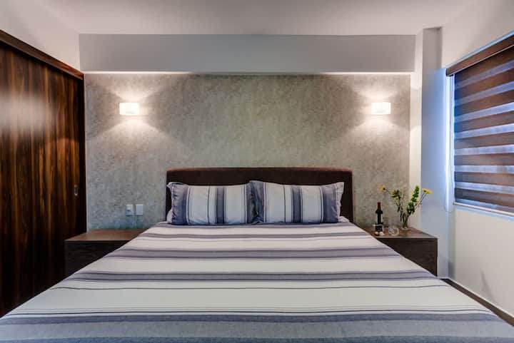 Habitación cómoda con una cama bien hecha, iluminación suave y una pared de acento con textura