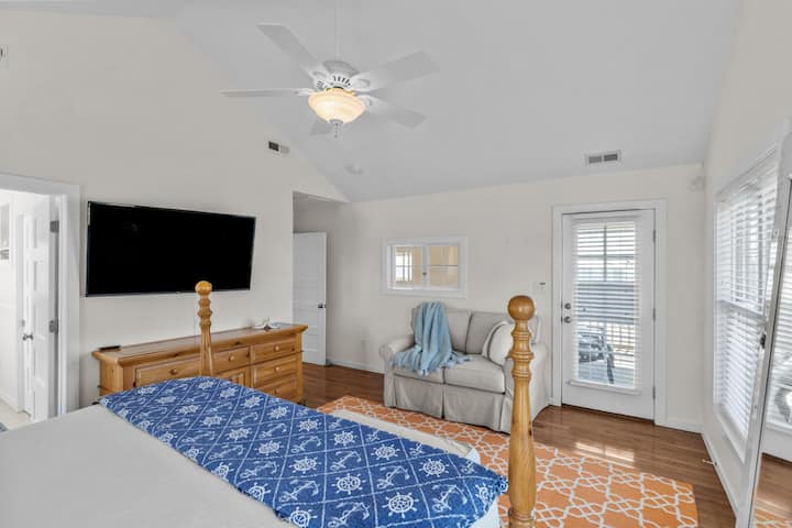 Relájate en el dormitorio principal con cama tamaño king, TV, asientos acogedores y cómodo acceso a los espacios exteriores
