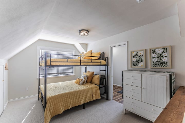 À l’étage, chambre loft ouverte avec lits superposés taille queen et salle de bain complète.