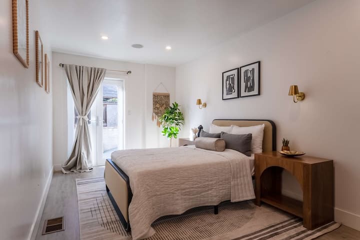 Habitación en la planta baja con cama matrimonial, televisión y acceso a la entrada que conduce al patio trasero. 