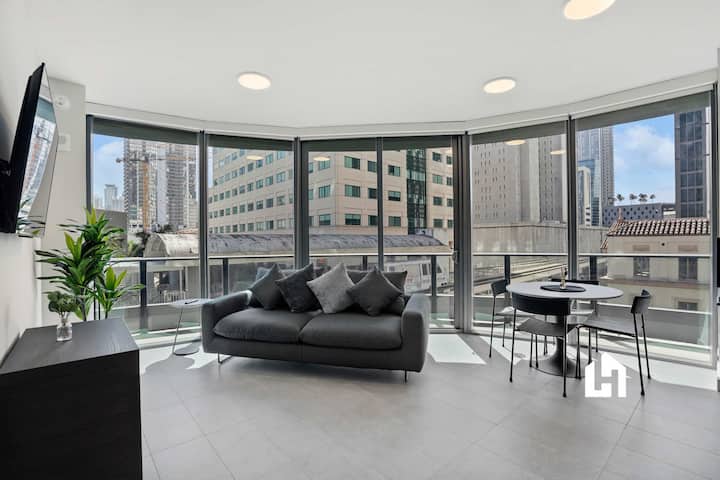 Sala de estar luminosa con ventanales de piso a techo y vistas a la ciudad.