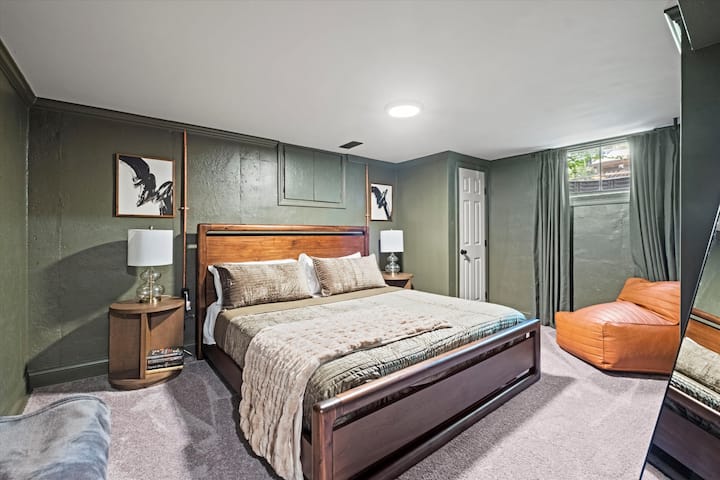 Basement king bedroom with plush carpeting, modern furnishings, and a spacious layout. A private lower-level retreat offering comfort and quiet, perfect for relaxing after a day exploring Kansas City.