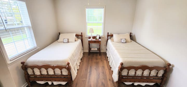 Habitación doble luminosa con pisos de madera y camas clásicas de madera